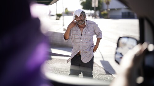 A man, who is homeless, talks to Maribel Padilla, left, of the Brown Bag Coalition, after receiving a cold, wet towel, Thursday, July 20, 2023, in Calexico, Calif.  Once temperatures hit 113 degrees Fahrenheit (45 Celsius), Padilla and the Brown Bag Coalition meet up with people who are homeless in Calexico, providing them with cold, wet towels, and some refreshments to help them endure the scorching temperatures.  (AP Photo/Gregory Bull)